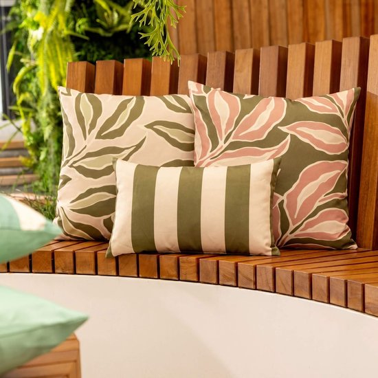 Trois coussins sur un banc en bois. Deux avec imprimé feuilles rose/vert, un avec rayures beige/vert.