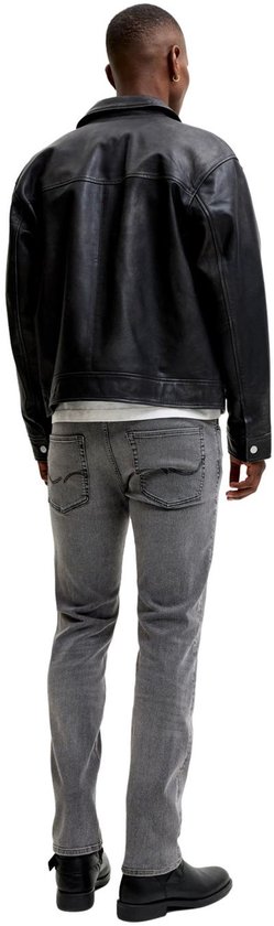 Achterkant man met zwarte leren jas, wit T-shirt en grijze jeans.