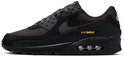 Zijkant van een zwarte Nike Air Max 90 sneaker met gele 'AIR MAX' opdruk.