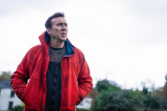 Man in felrode jas, met een gebreide trui eronder. Hij kijkt naar de verte.