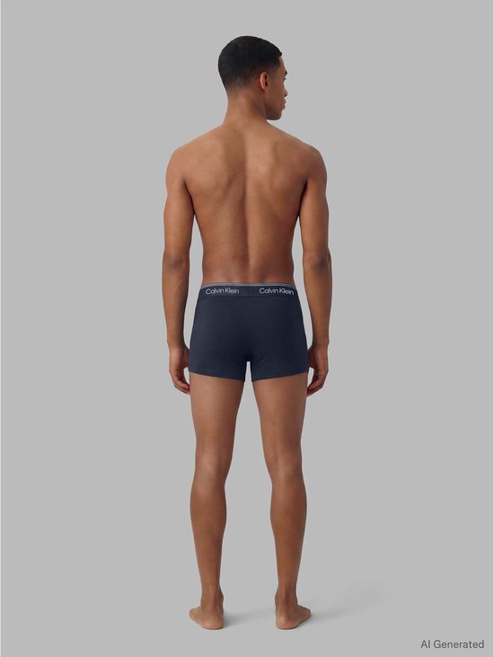 Man met navy Calvin Klein trunks, staand van achteren gezien.