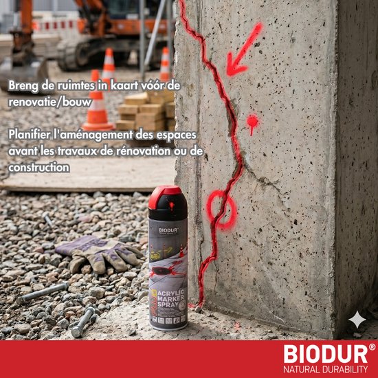 Spuitbus met rode markering op een betonnen muur met scheuren, handschoenen en bouwmachines.