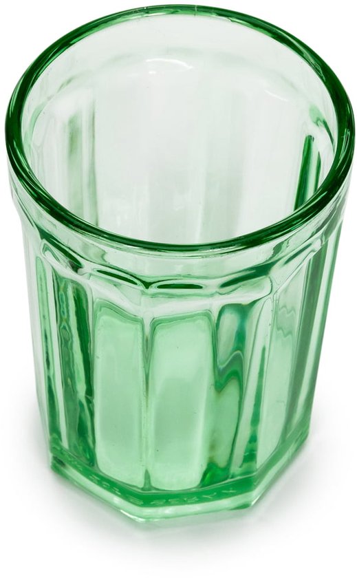 Eén groen, facetgeslepen glas, op wit oppervlak.