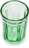 Eén groen, facetgeslepen glas, op wit oppervlak.