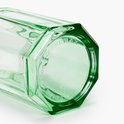 Detail van de onderkant van een groen, facetgeslepen glas met ingegraveerde tekst.