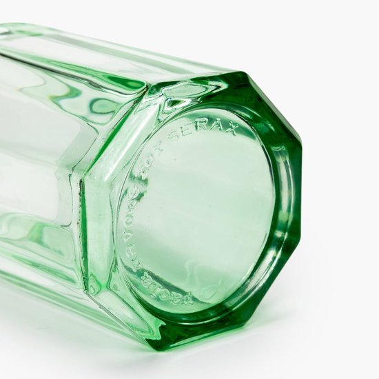 Detail van de onderkant van een groen, facetgeslepen glas met ingegraveerde tekst.
