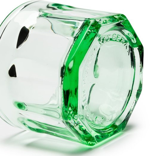 Detail van de zijkant van een groen, facetgeslepen glas met ingegraveerde tekst.