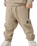 Detail van een beige joggingbroek met een zwart logo en ritszak.