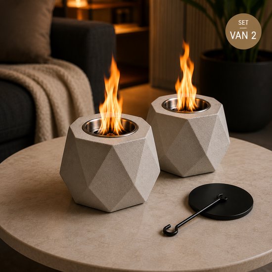 Twee lichtgrijze betonnen tafellampjes met vlammen op een salontafel.