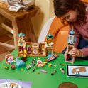 Meisje bouwt aan LEGO Disney Rapunzel's Kasteel met figuren, meubels en een tablet met instructies.