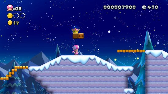 Toad met roze muts en jurk springt, onder een kroon op een steenblok in een besneeuwd landschap.