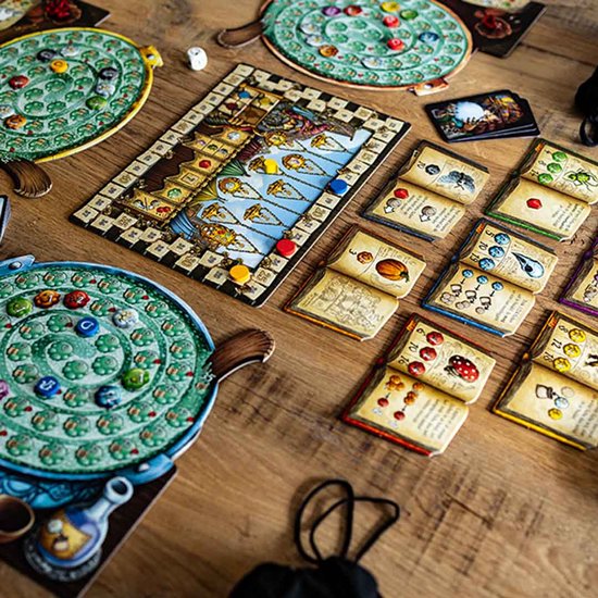 Overzicht van het bordspel De Kwakzalvers van Kakelenburg met spelborden, kaarten en fiches op een houten tafel.