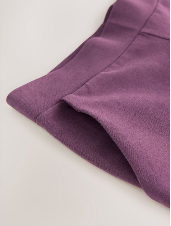 Detailopname van de tailleband en de zak van een paarse tricot broek.