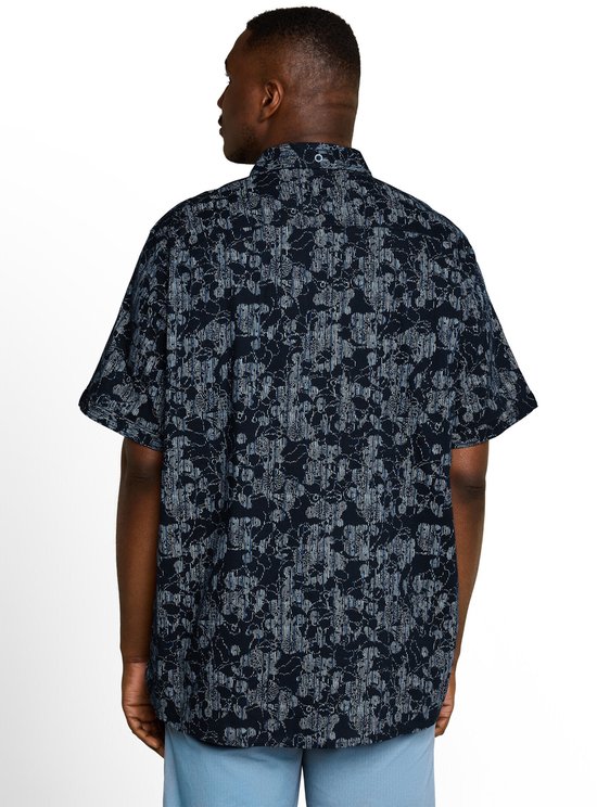 Man van achteren, draagt een donkerblauw katoenen overhemd met korte mouwen en een lineair patroon.
