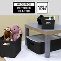 Zwarte opbergboxen met speelgoed en een tafeltje, met informatie "Made from recycled plastic" en "Made in NL/EU".
