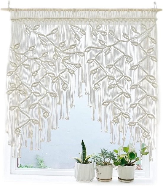 Beige macramé gordijn met bladpatroon, hangend voor een raam met planten.