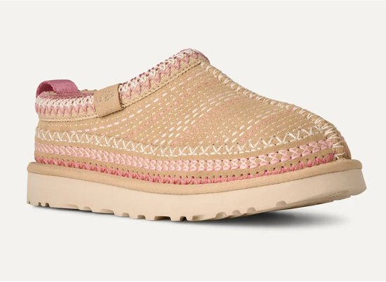 Beige UGG pantoffel met roze en witte stiksels, een dikke beige zool en een roze lus.