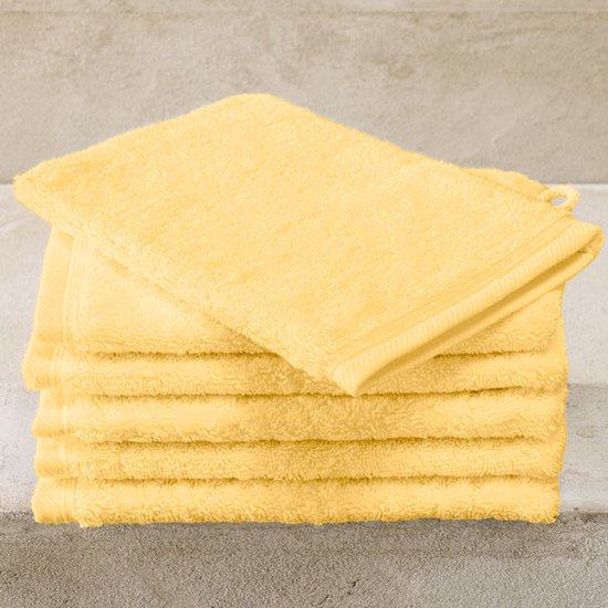 Stapel gele washandjes op een betonnen achtergrond.