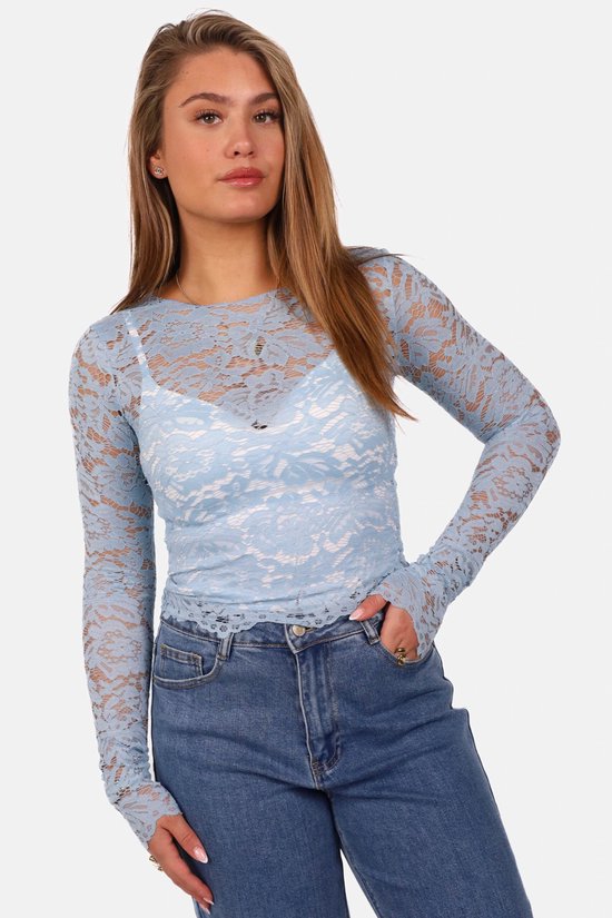 Gros plan sur un mannequin portant un haut bleu clair en dentelle sur un bandeau blanc et un jean.