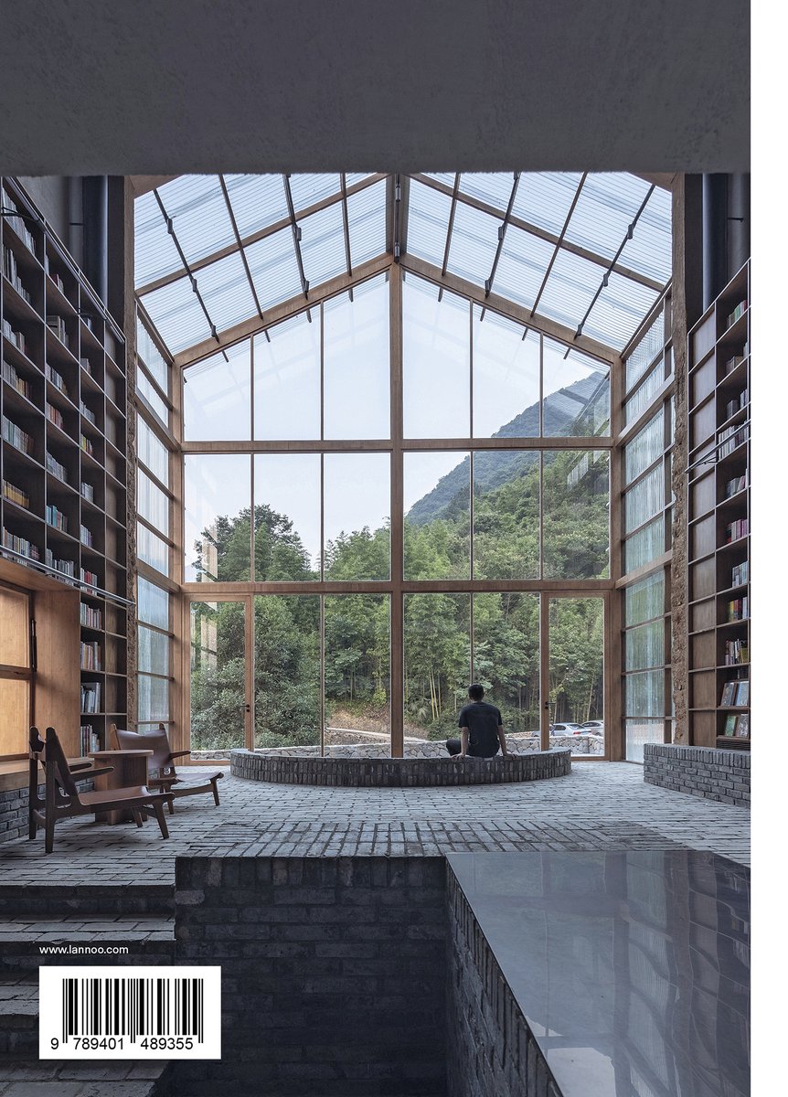 Man zit in een grote, lichte bibliotheek met hoge boekenkasten en een glazen dak met uitzicht op bergen.