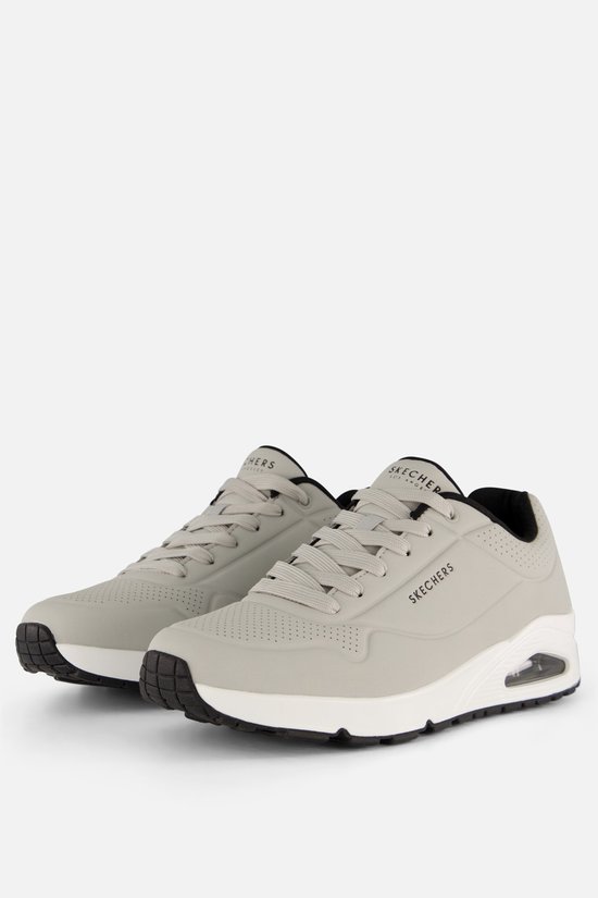 Grijze Skechers Uno sneakers met witte zolen en zwarte randen.