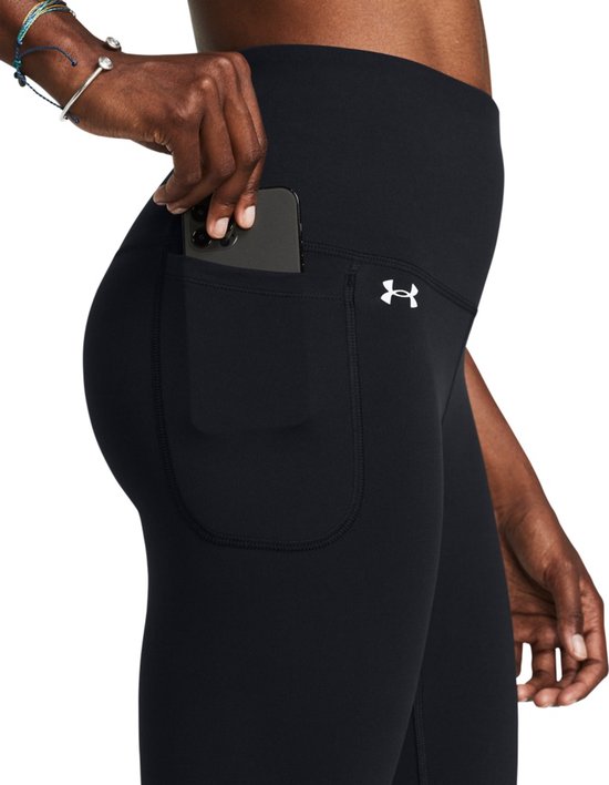 Close-up van de heup van een zwarte legging met hoge taille, met een grote zijzak waarin een smartphone wordt geplaatst.