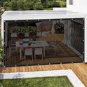 Een terras met eettafel en stoelen, beschermd door transparante zijwanden.
