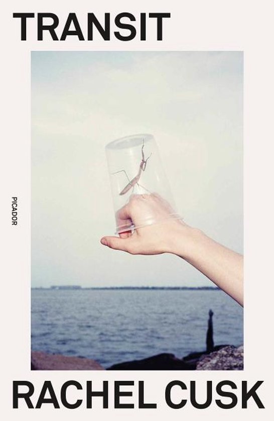Een hand houdt een doorzichtige beker met daarin een bidsprinkhaan vast, met de zee op de achtergrond. De titel 'TRANSIT' staat bovenaan.