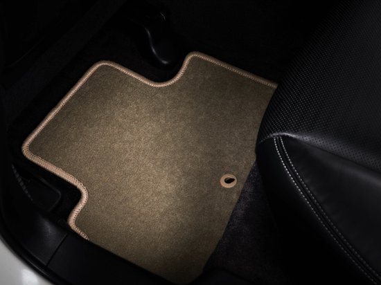 Beige voormat met beige bies geplaatst in de bestuurdersvoetruimte van een auto.
