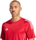 Close-up van een man in een rood adidas sportshirt met witte strepen op de schouders.