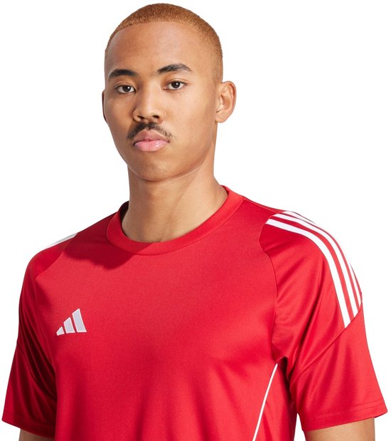 Close-up van een man in een rood adidas sportshirt met witte strepen op de schouders.