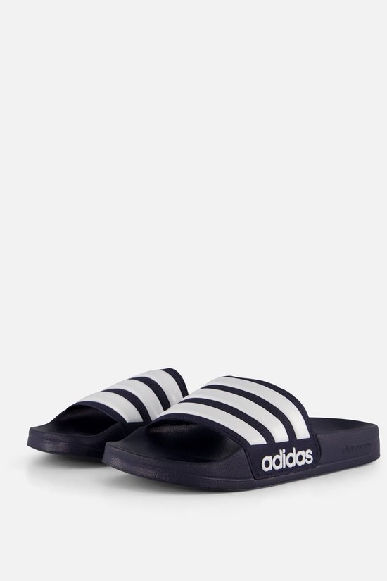 Donkerblauwe adidas slippers met witte strepen en logo.