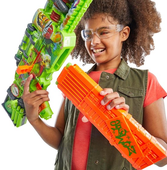 Meisje met beschermende bril lacht terwijl ze een felgroene Nerf Zombie Corrupter blaster en een oranje magazijn vasthoudt.