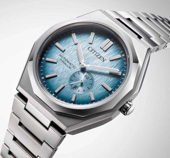 Citizen horloge met zilverkleurige titanium kast en band. Lichtblauwe wijzerplaat met geborstelde textuur en datumvenster.