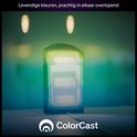 Une lampe Philips Hue Play noire émettant une lumière verte, jaune et bleue dans une pièce.