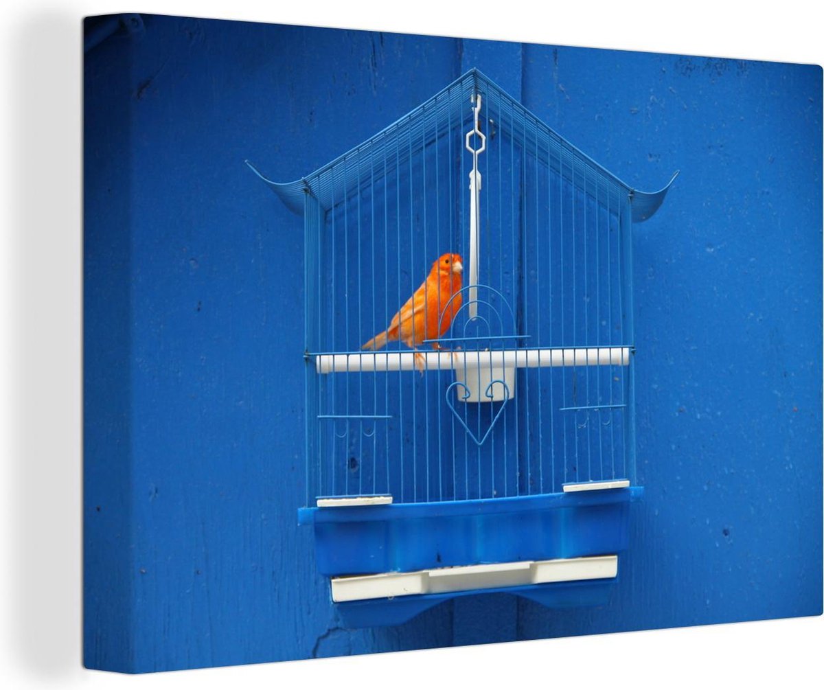 Canvas Schilderij Kanarie in een kooi tegen een blauwe muur - 90x60 cm - Wanddecoratie op Prijzenvolger.com
