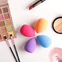 Make-up spullen: oogschaduw palette, twee kwasten, lipstick, make-up sponzen en poeder.