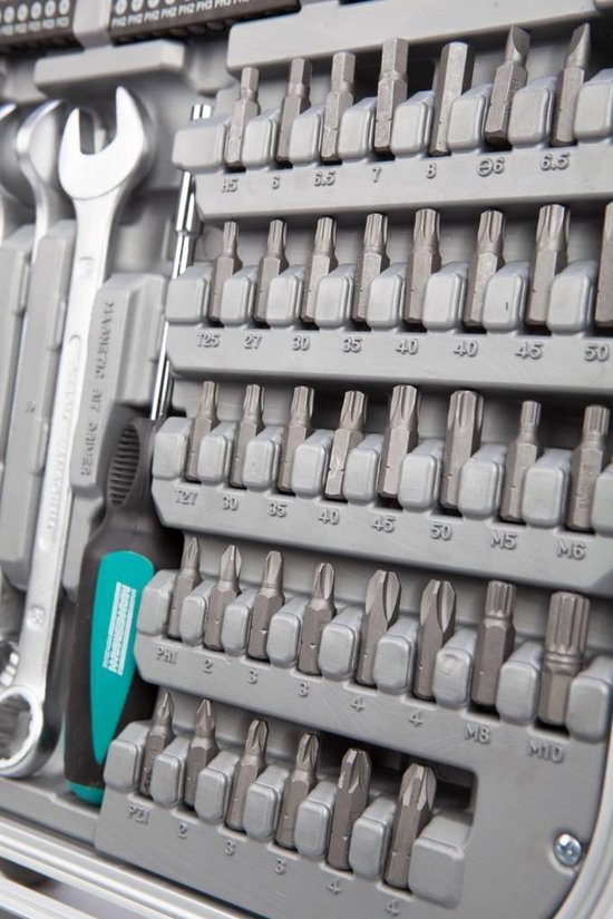 Gedetailleerde weergave van bit-set met maten, schroevendraaier en sleutel in een grijze gereedschapskoffer.