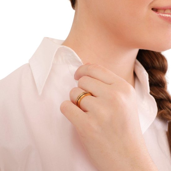 Femme avec tresse porte une bague dorée avec petites pierres claires à son doigt.