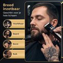Man met baard wordt getrimd met zwarte tondeuse, met afbeeldingen van hoofdhaar, baard, borst en buik trimmen.