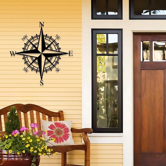 Décoration compas noire sur la façade d'une maison, à côté d'un banc en bois.