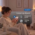 Vrouw houdt een Luvion monitor vast in de woonkamer met functies voor terugspreekfunctie en voedingstimer.
