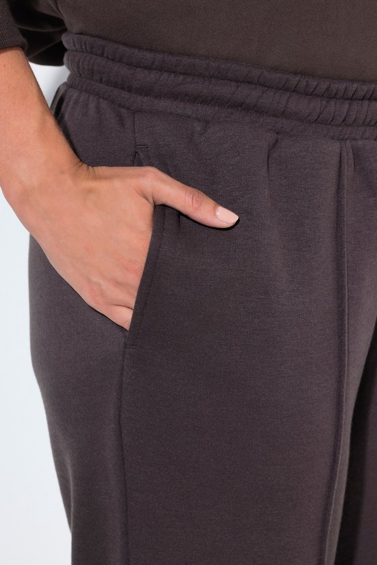 Detailopname van de zak van een donkerbruine joggingbroek met elastische tailleband.