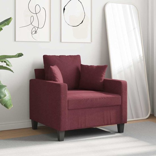 Wijnrode fauteuil met losse kussens in een modern interieur met spiegel.
