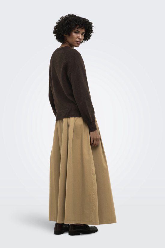 Bruine gebreide trui met gouden knopen, gedragen door een vrouw in een beige rok.