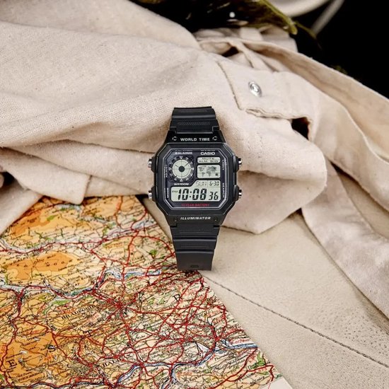 Zwart digitaal Casio-horloge op een gedetailleerde kaart met een beige kledingstuk op de achtergrond.