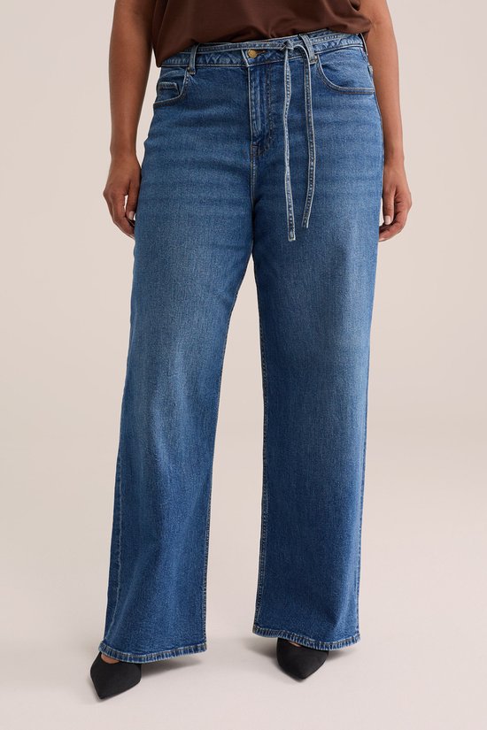 Model in een wijde spijkerbroek met strikceintuur en een middelhoge taille.