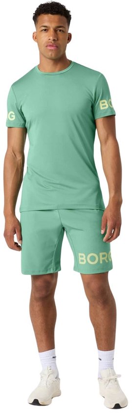 Man in een mintgroen sportshirt met beige logo op de mouwen en bijpassende mintgroene sportshort.