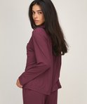 Model kijkt over de schouder, draagt een paars pyjamashirt met lange mouwen en borstzak.