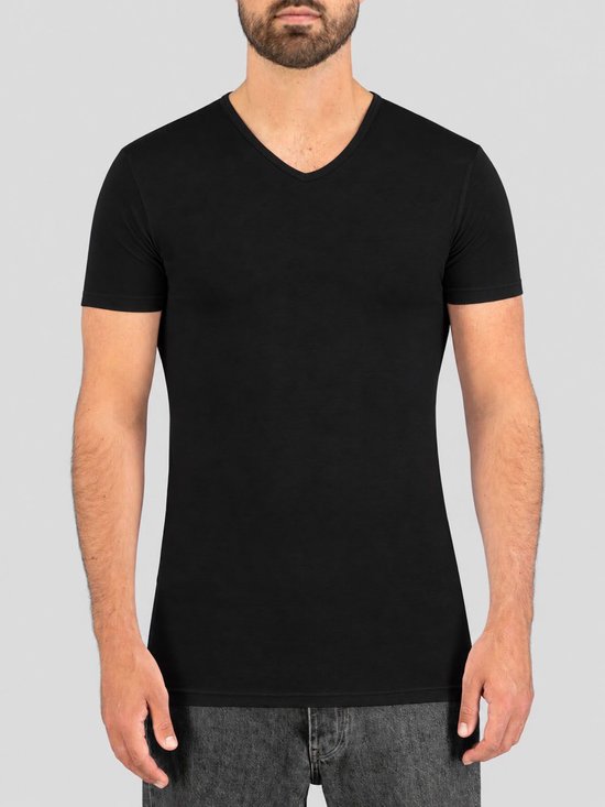 Model draagt een aansluitend zwart V-hals T-shirt met korte mouwen van biologisch katoen.